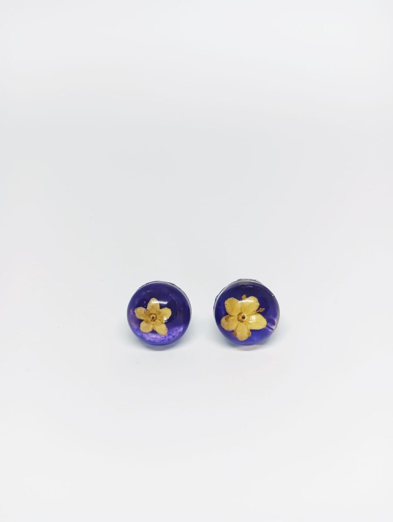 pendientes hechos de flores naturales y sauco con fondo morado